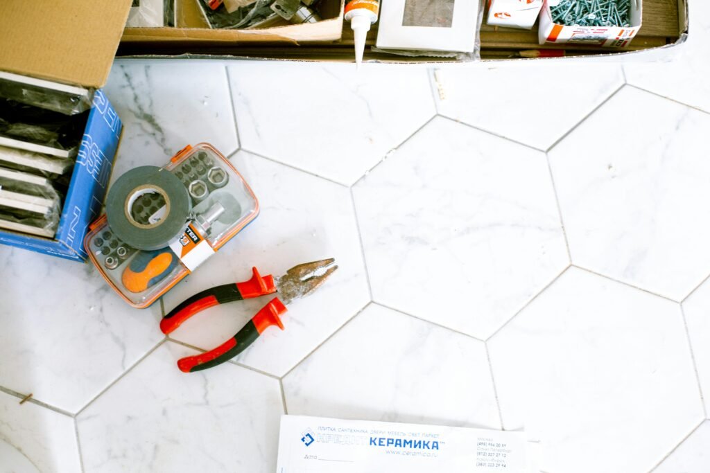 A selection of home renovation tools placed on a white tiled floor, ready for use.